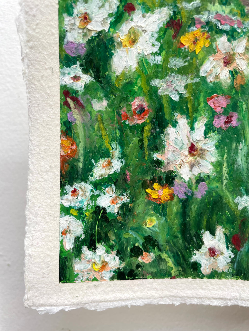 A close-up of a textured white paper featuring an impressionistic painting of white daisies and other wildflowers with vibrant green, yellow, pink, and orange brushstrokes.