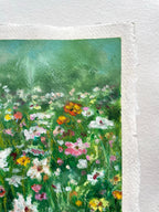 A close-up of an oil pastel artwork on paper featuring an impressionistic wildflower meadow with green foliage and colorful blossoms.