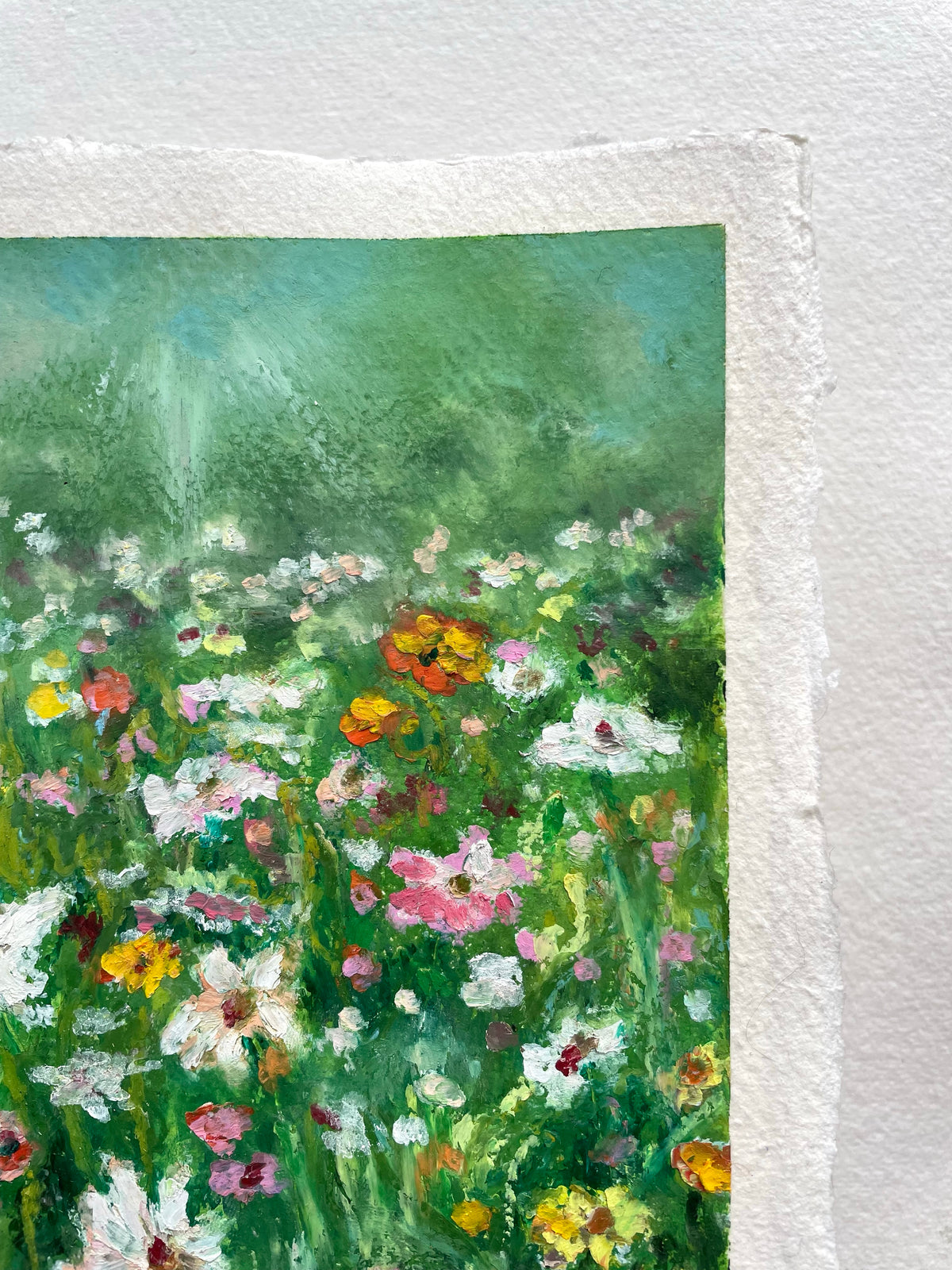 A close-up of an oil pastel artwork on paper featuring an impressionistic wildflower meadow with green foliage and colorful blossoms.