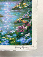 Close-up of a textured oil pastel painting on white paper, showing a forest scene with blue water, green foliage, and colourful flowers. The artist's signature is visible at the bottom.