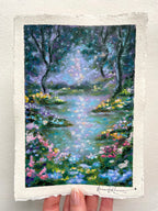 An oil pastel painting of a forest stream surrounded by colourful wildflowers, with a textured off-white paper border and a visible artist signature at the bottom.