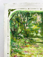 A close-up of an oil pastel painting on textured paper, depicting a lush green forest scene with trees, a rabbit and a grassy meadow dotted with pink and yellow flowers. The paper corner is visible with a green decorative border.