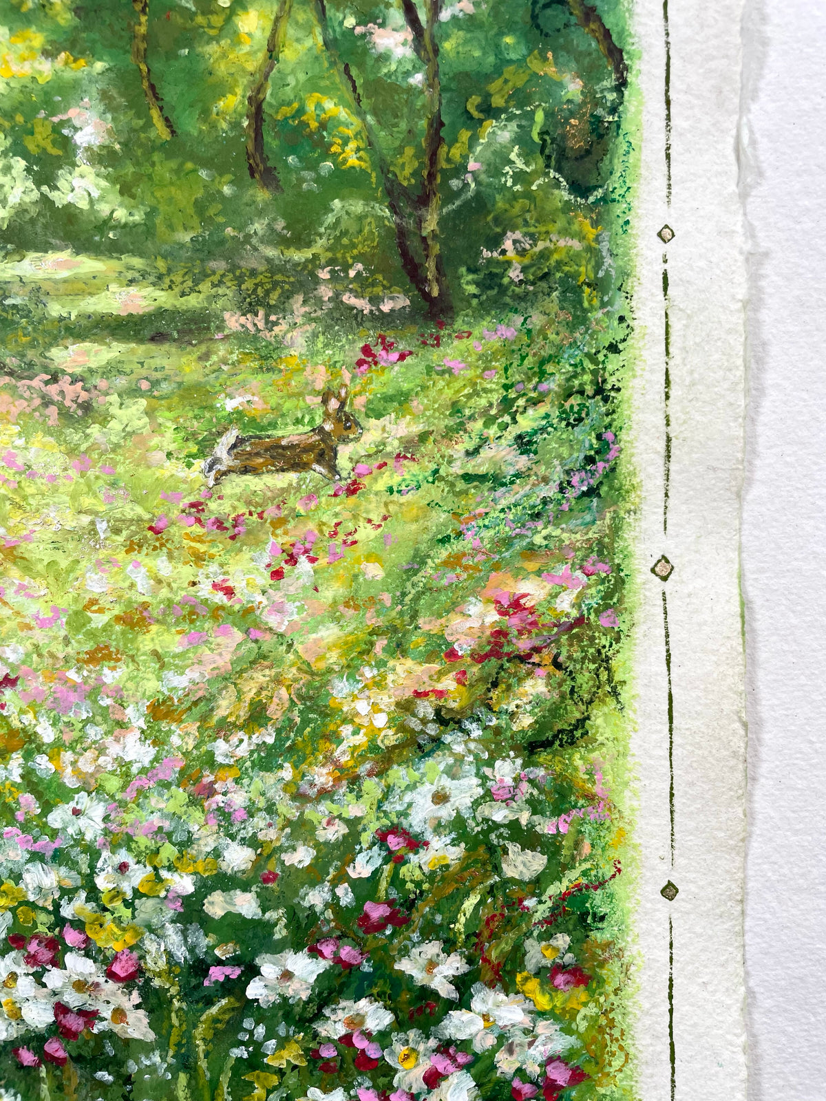 A close-up of an oil pastel painting depicting a lush green meadow filled with white, pink, and yellow wildflowers, with a rabbit visible in the background among trees. The right edge shows the textured, slightly torn edge of the paper.