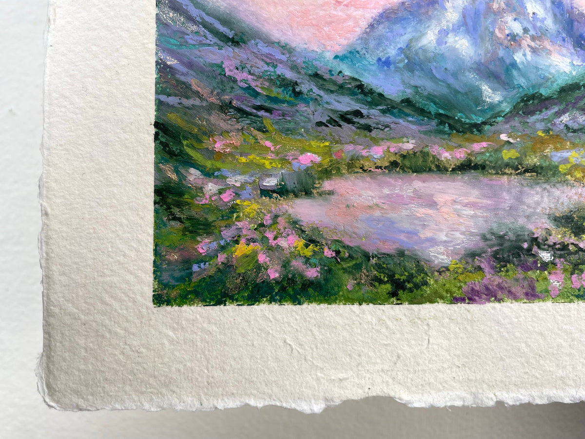 Close-up of a textured oil pastel painting on white paper, showing a landscape with mountains, a lake, and pink flowers in soft pastel tones.