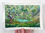 An oil pastel painting on textured white paper, depicting a lush green landscape with a large tree, a swing, and a turquoise lake. The artist’s signature is in the bottom right corner.