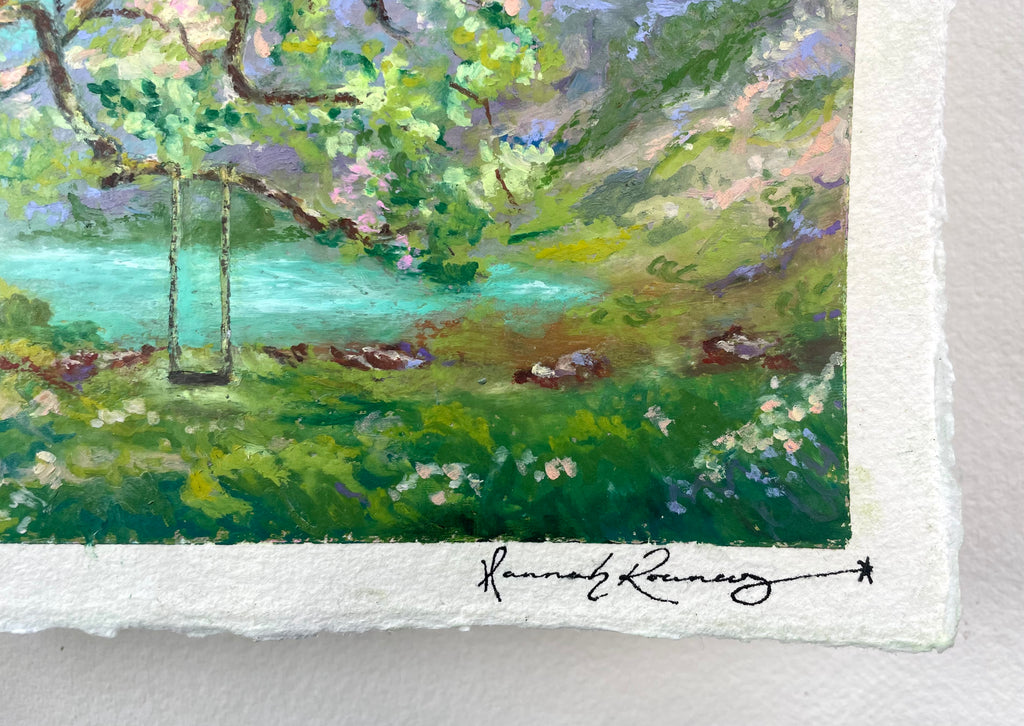 Close-up of an oil pastel painting on textured white paper, showing a landscape with green foliage, a turquoise body of water, and a swing in the tree, signed by the artist.