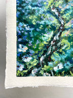 A close-up of a textured oil pastel painting on white paper, depicting lush foliage, white blossoms and a stream.