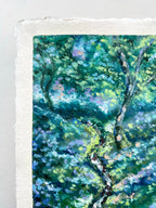 A close-up of a textured oil pastel painting depicting a lush green forest with dappled sunlight and purple-blue floral accents, printed on white handmade paper with a visible deckled edge.