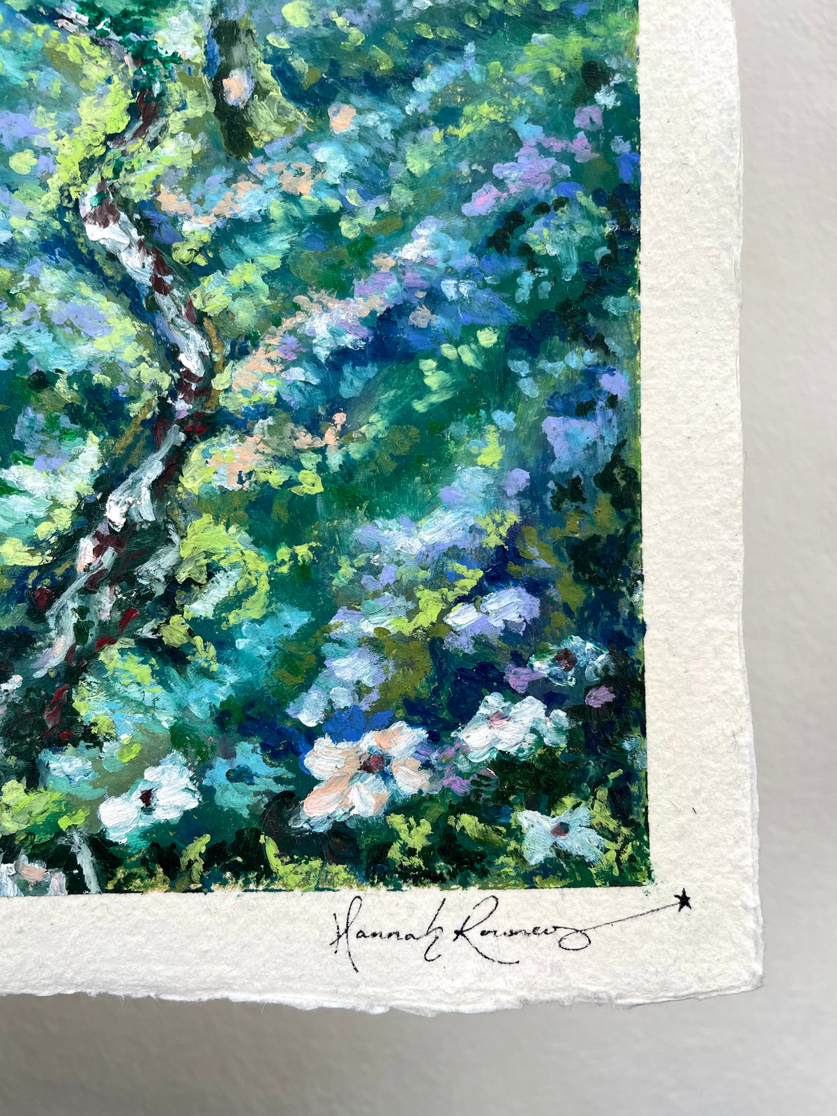 Close-up of a textured oil pastel painting showing green and blue foliage with white and purple flowers, featuring a white paper border and an artist signature at the bottom.