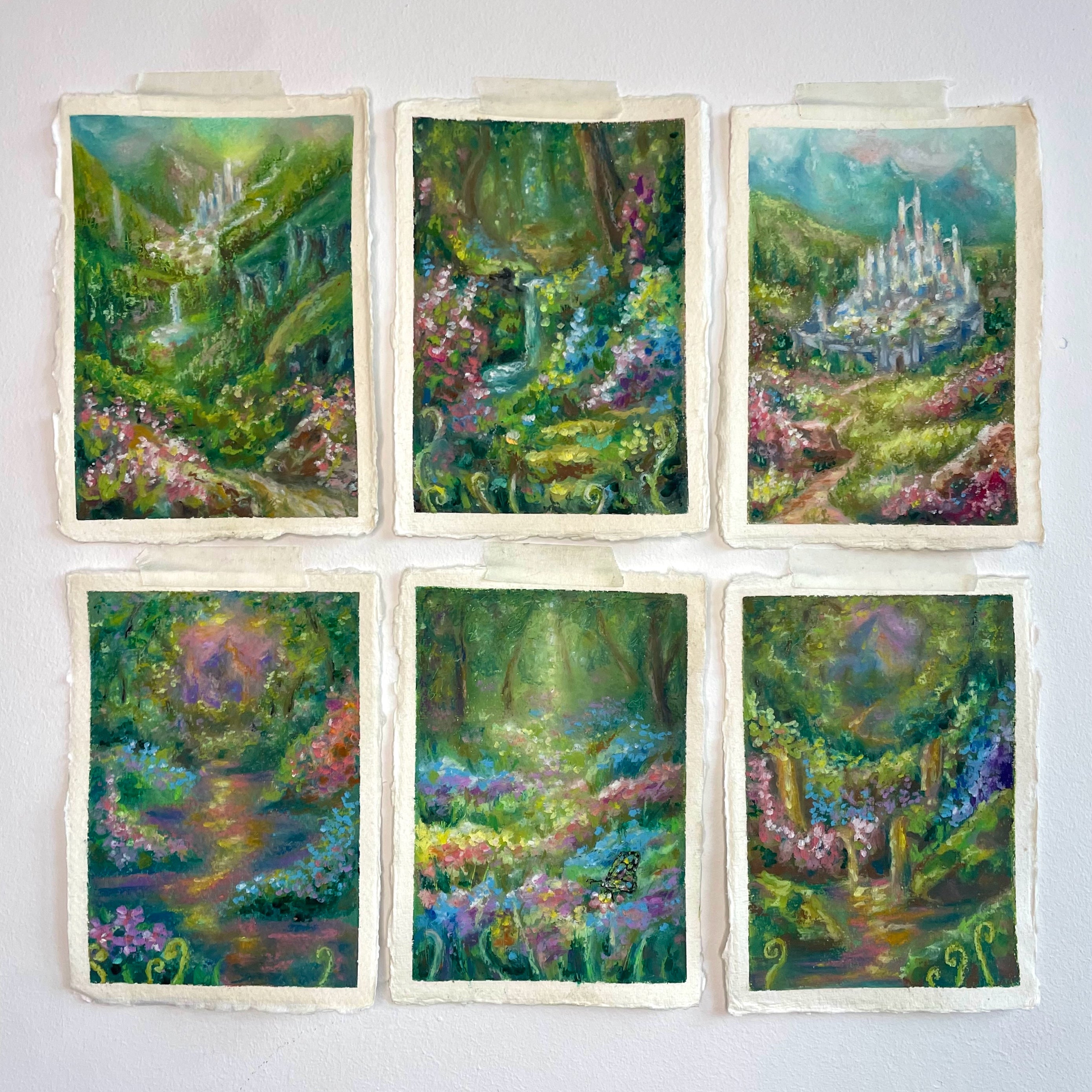 Gallery wall of six whimsical mini original oil pastel paintings featuring fairytale forests, waterfalls, castles, rivers, lush foliage, and colourful magical woodland scenery.