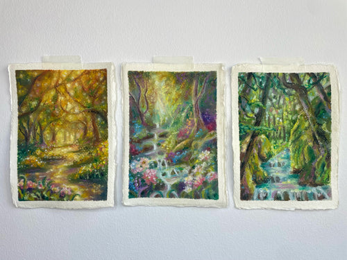 Three whimsical forest themed artworks displayed side-by-side, inspired by autumn, spring, and summer with glowing rivers, waterfalls, sunlight, trees, and wildflowers.