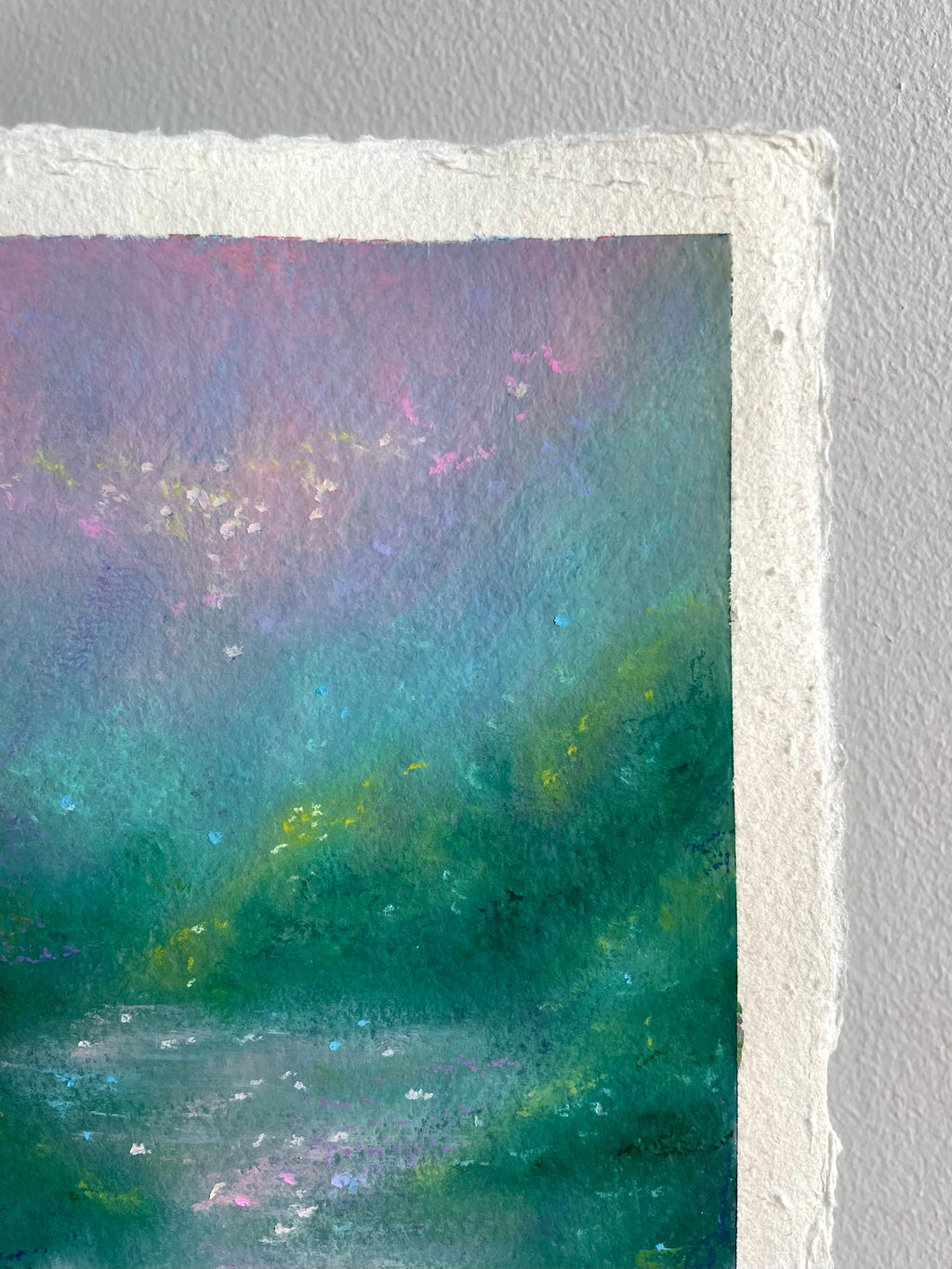 A close-up of a textured paper original painting featuring an impressionistic landscape with shades of teal, green, purple, and pink.