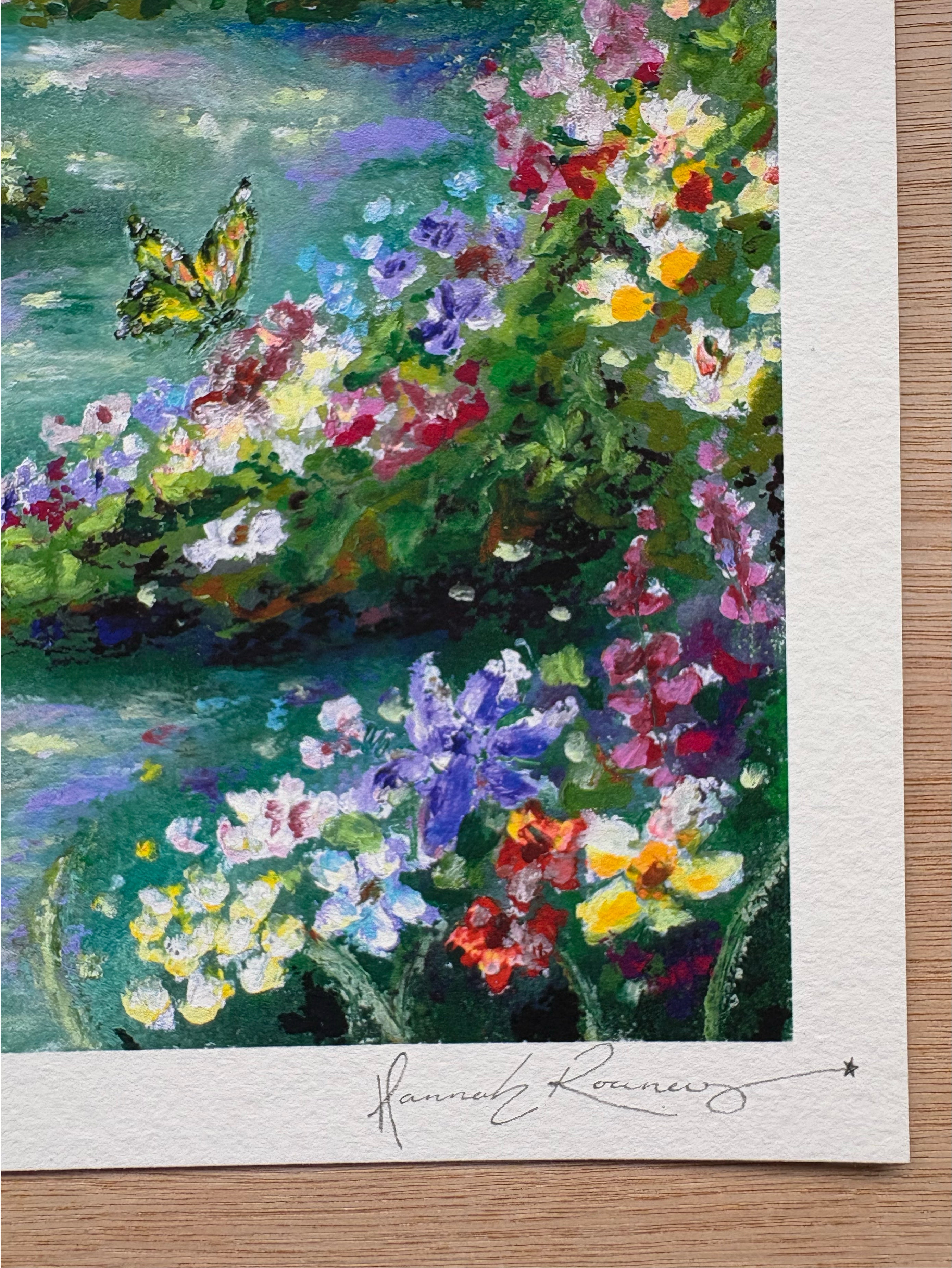 Close-up detail of “Looking for Wonderland” giclée print showing hand-signed pencil signature, colourful wildflowers, green butterfly, and rich oil pastel texture.
