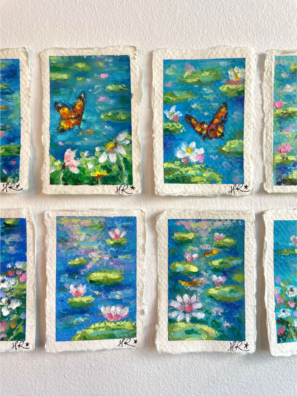 Cropped view of whimsical mini oil pastel pond painting collection focusing on central artworks featuring water lilies, lily pads, and magical nature scenes.