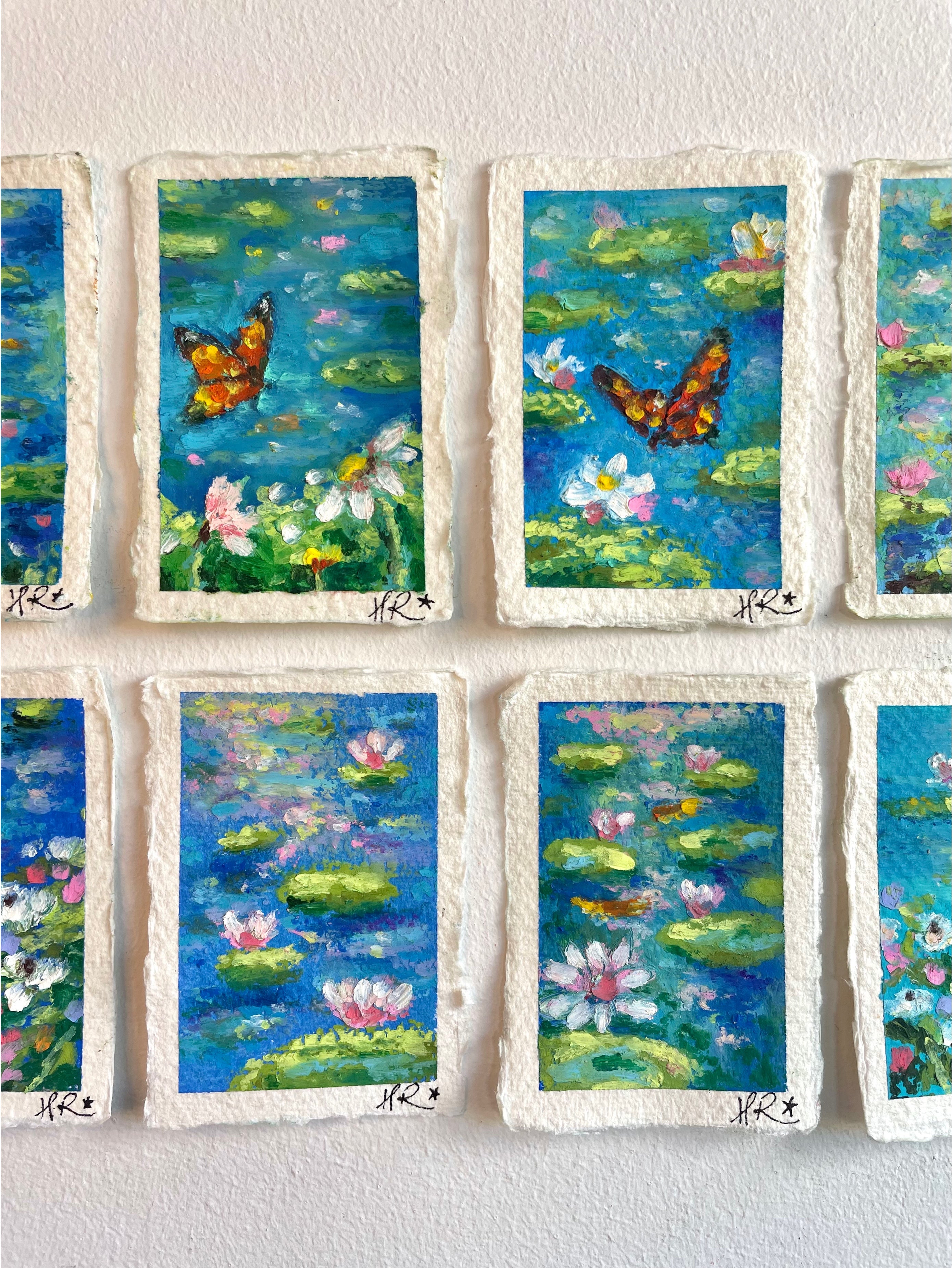 Cropped view of whimsical mini oil pastel pond painting collection focusing on central artworks featuring water lilies, lily pads, and magical nature scenes.