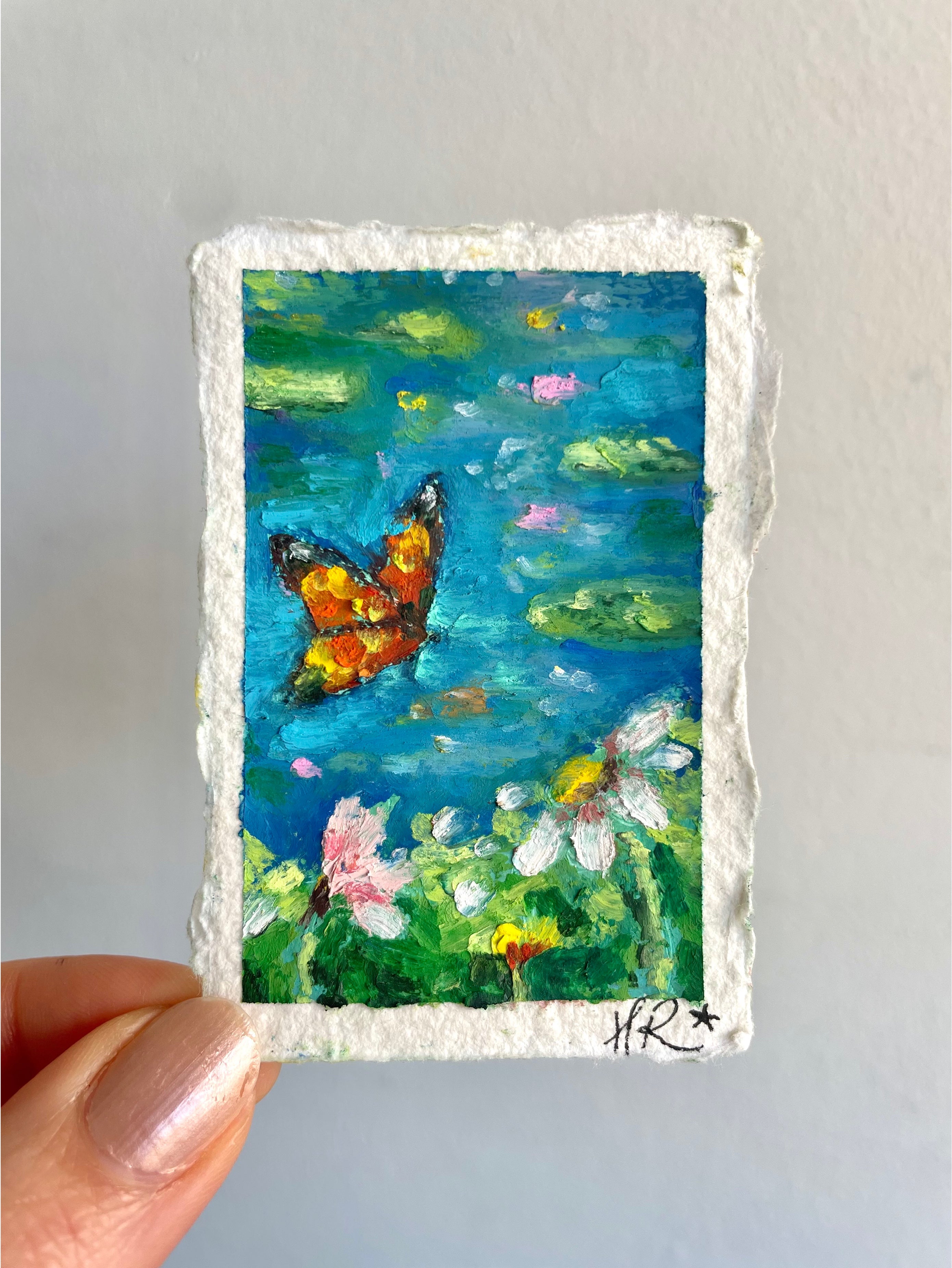 Mini oil pastel pond painting featuring butterfly coming in to land above lily pads and wildflowers in a vibrant blue water landscape.