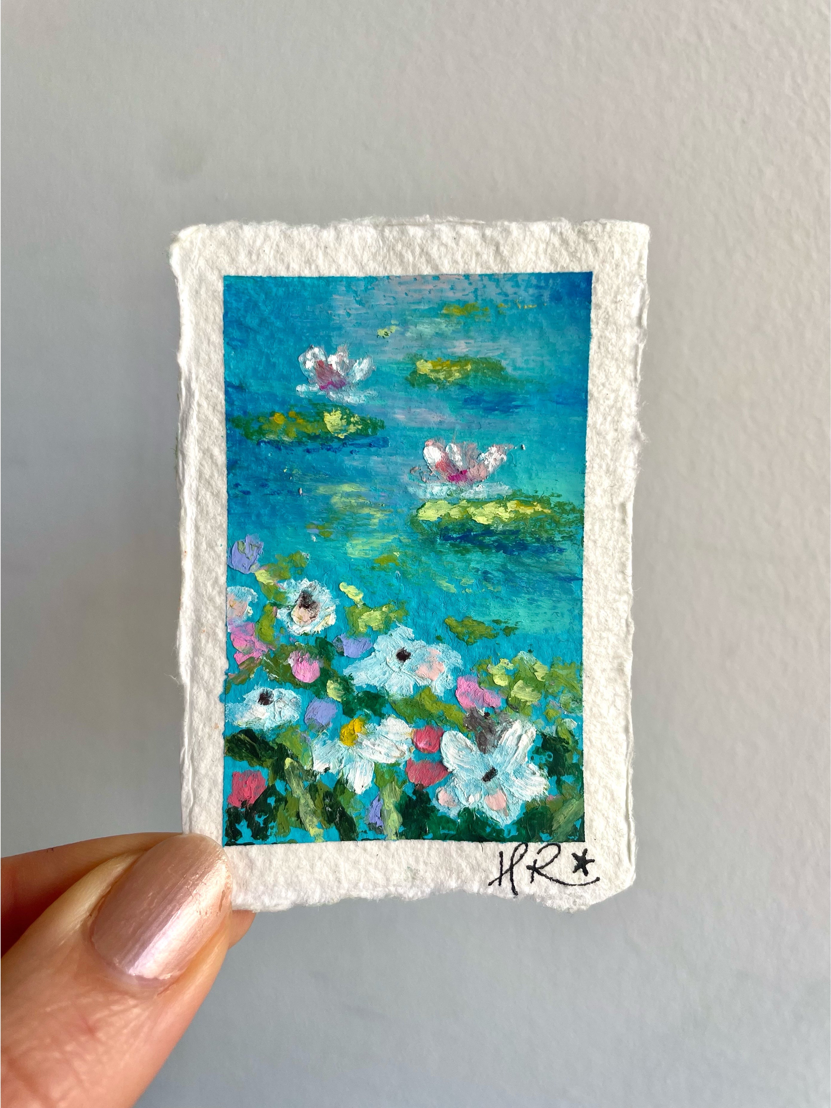 Whimsical mini oil pastel pond painting featuring striking turquoise water, water lilies, lily pads, and wildflowers along the shoreline.