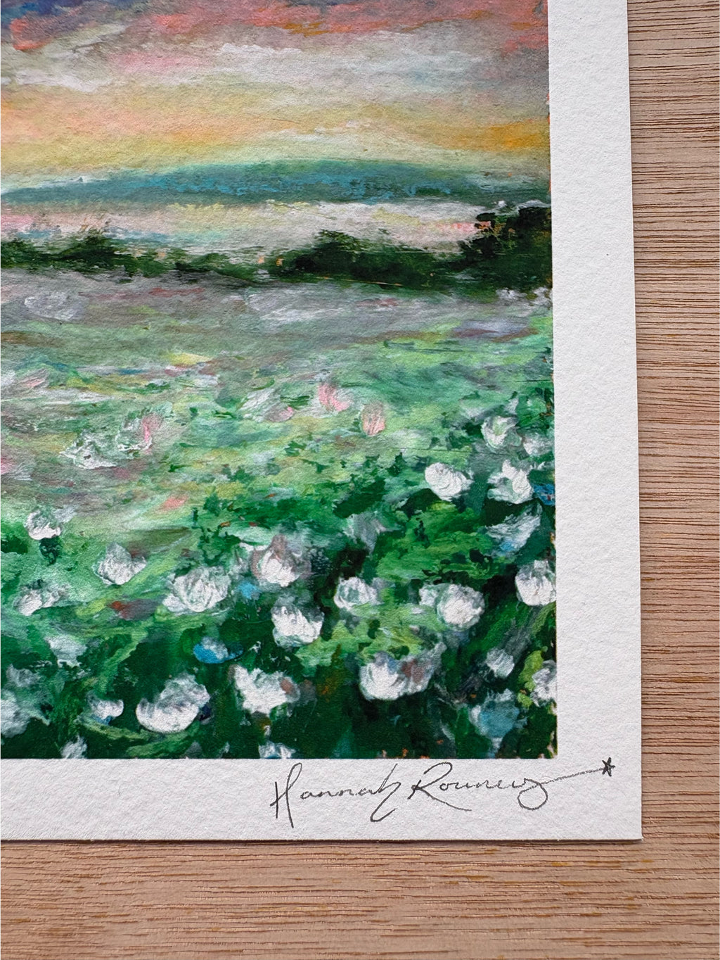 Close-up detail of dreamy landscape giclée print showing white wildflowers, deep green grass, distant lake, and hand-signed pencil signature.