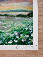 Close-up detail of dreamy landscape giclée print showing white wildflowers, deep green grass, distant lake, and hand-signed pencil signature.
