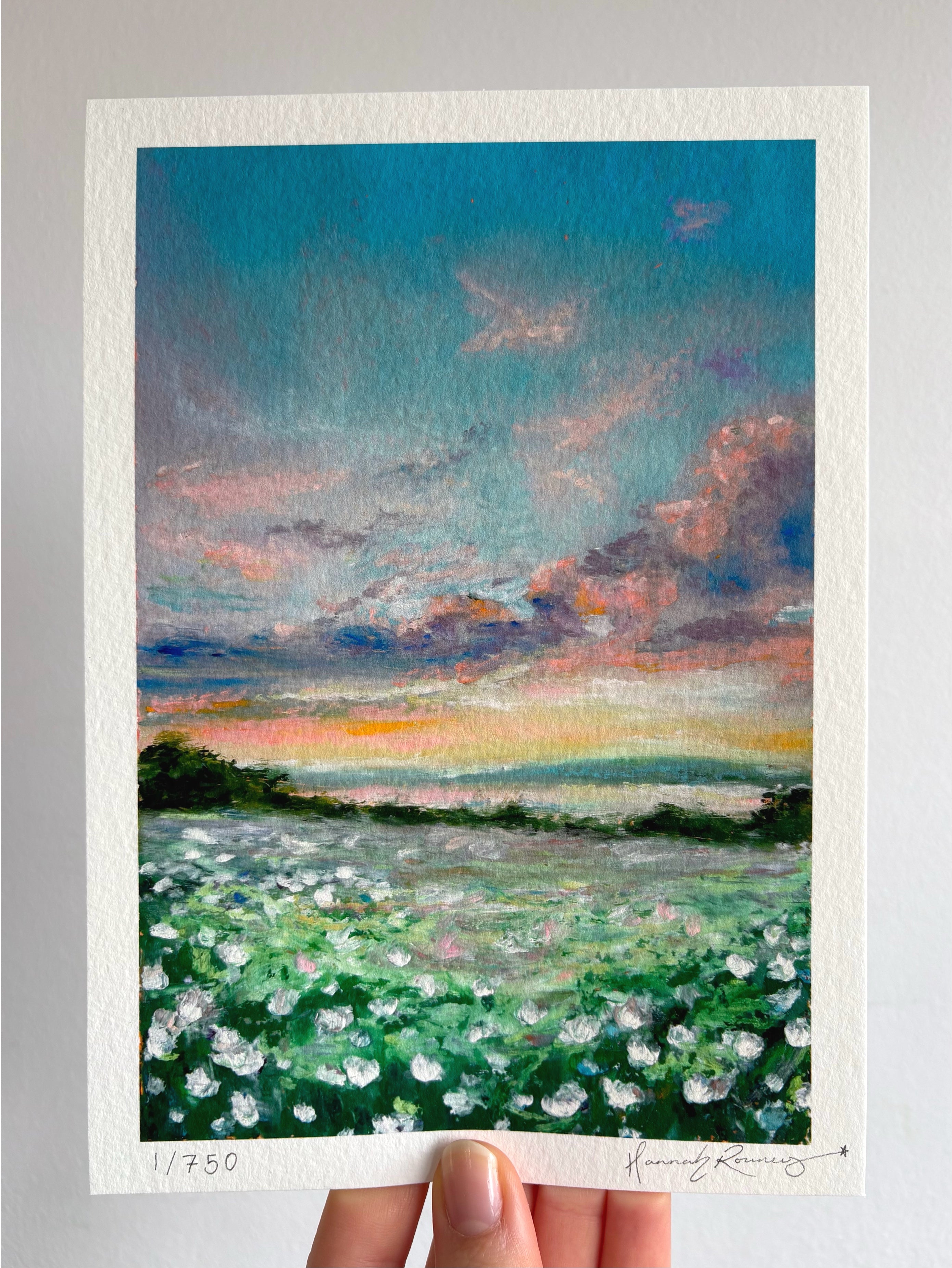 Limited edition giclée fine art print of dreamy sunset landscape with magical sky and wildflowers held against a white wall.