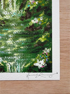 Close-up detail of enchanted forest giclée print showing foreground waterfall, white wildflowers, and hand-signed pencil signature.