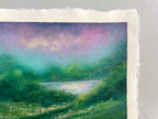 A close-up of an oil pastel landscape painting on textured paper, showing a green field, a reflective lake, and a purple and teal sky, mounted against a light gray wall.