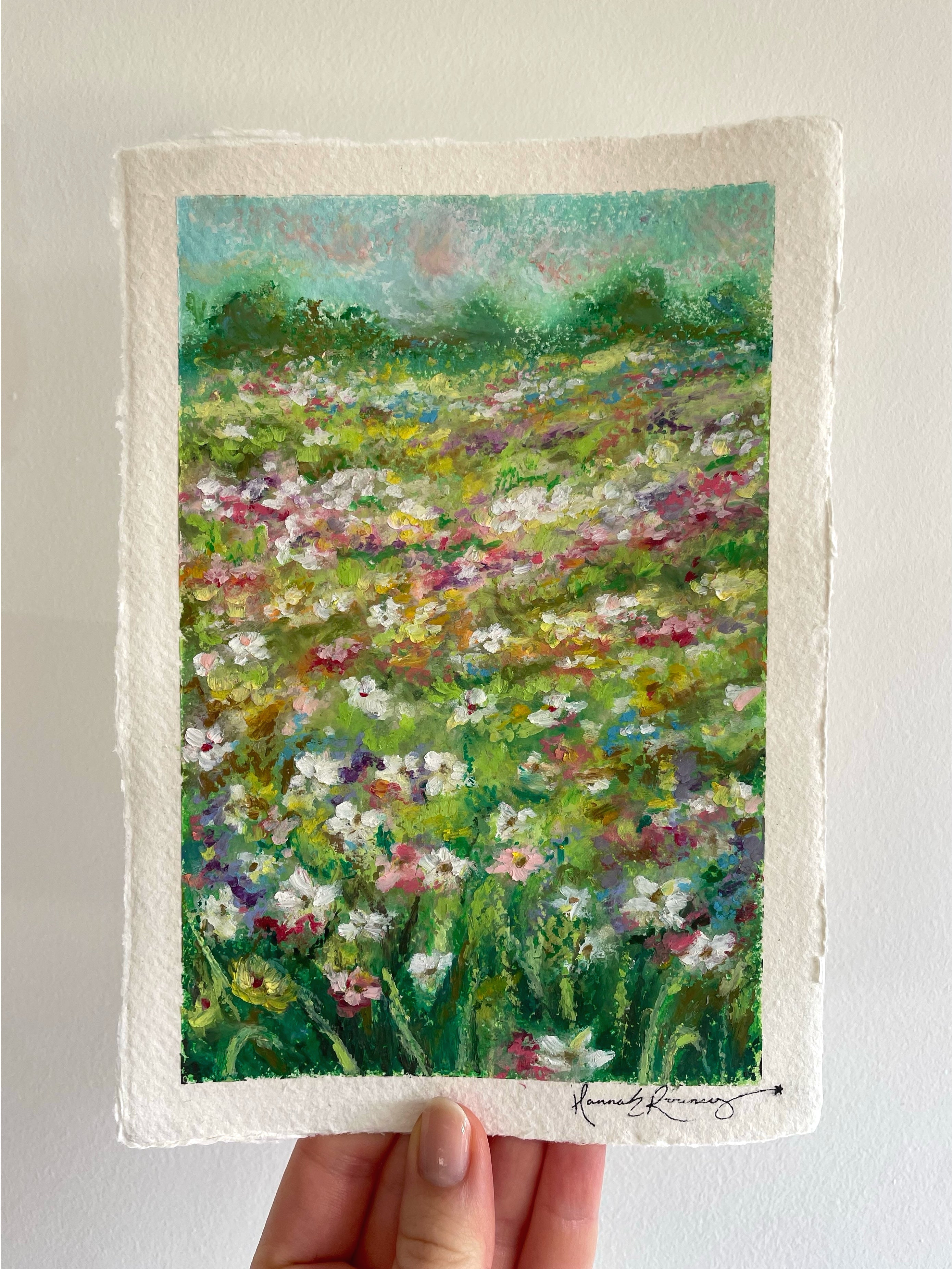 Original oil pastel wildflower field painting held in hand, featuring bright spring colours, blooming meadow flowers, and joyful textured landscape inspired by the magic of springtime.