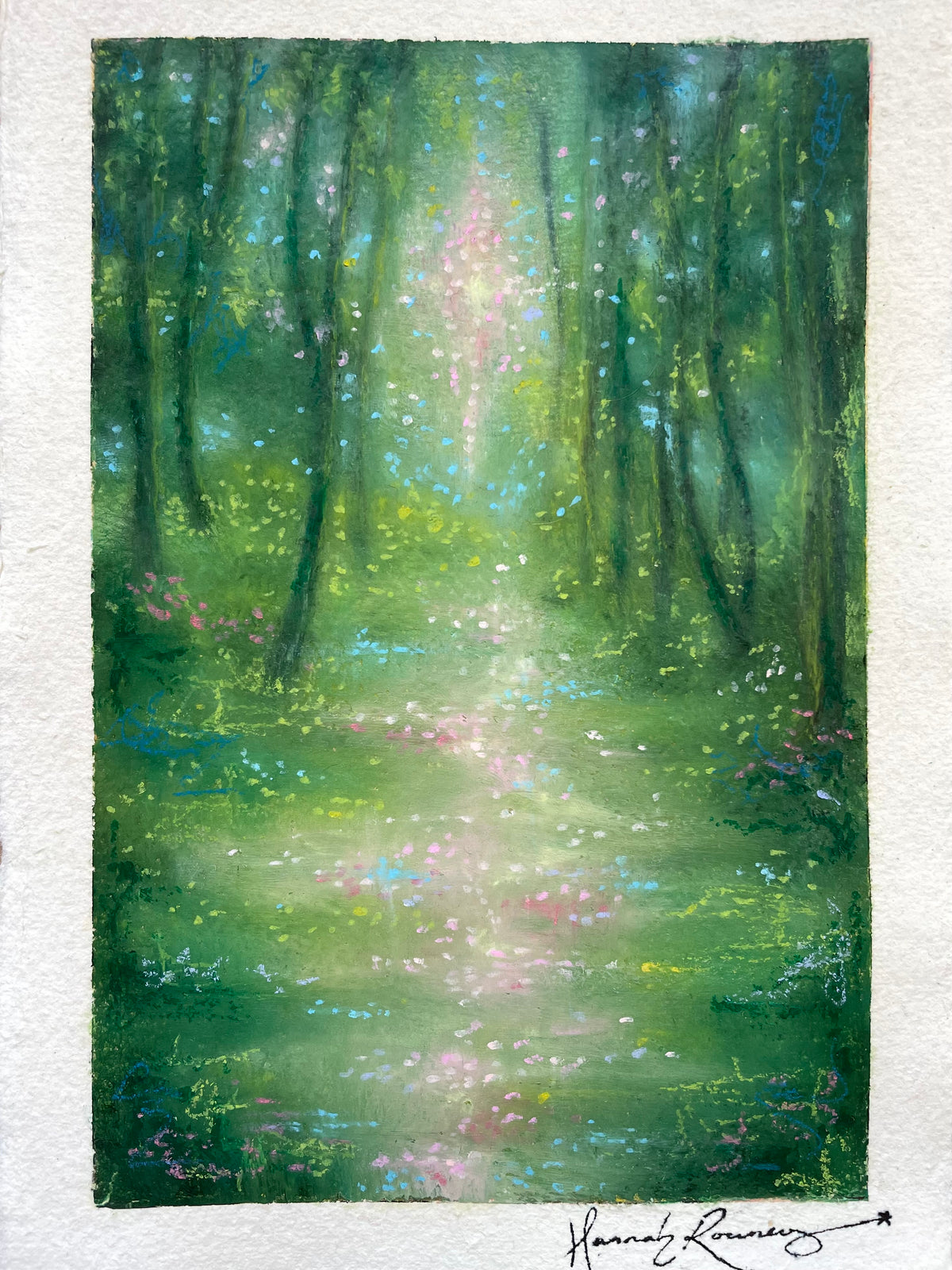 A vertical watercolor painting of a sunlit forest path with tall trees, glowing green and blue foliage, and soft pink highlights, shown on textured white paper with an artist signature at the bottom.